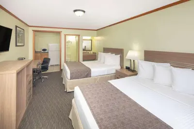 a hotel room with two beds and a desk at Travelodge by Wyndham Golden Sportsman Lodge in Golden