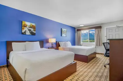 a hotel room with two beds and a blue wall at Days Inn by Wyndham Golden in Golden