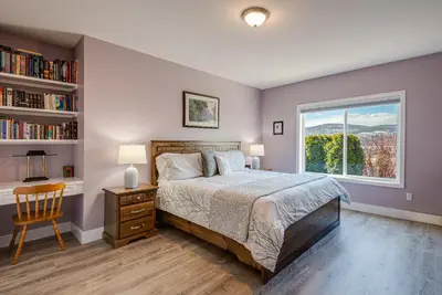 a bedroom with a bed and a window and a chair at Adela's Bed and Breakfast in West Kelowna