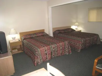 a hotel room with two beds and a television at Beach Grove Motel in Tsawwassen