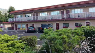 a hotel with cars parked in a parking lot at Swiss Sunset Inn in Penticton