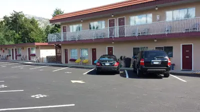 two cars parked in a parking lot in front of a building at Swiss Sunset Inn in Penticton