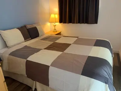 a bedroom with a bed and a lamp on a table at Swiss Sunset Inn in Penticton