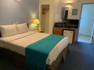 a hotel room with a large bed and a kitchen at Swiss Sunset Inn in Penticton