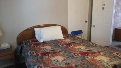 a bedroom with a bed with a pillow on it at Holiday House Motel in Penticton