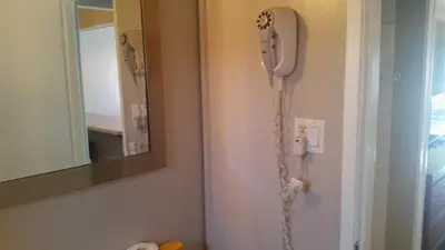 a phone hanging on a wall next to a mirror at Holiday House Motel in Penticton