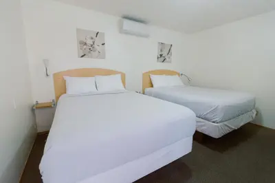two beds in a room with white sheets at Waterfront Inn in Penticton