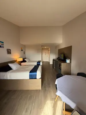 a hotel room with two beds and a desk at Sand Pebbles Inn in Qualicum Beach