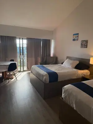 a hotel room with two beds and a desk at Sand Pebbles Inn in Qualicum Beach