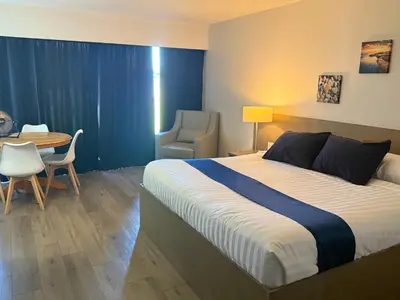 a bedroom with a bed and a table and a chair at Sand Pebbles Inn in Qualicum Beach