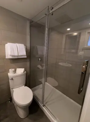 a bathroom with a toilet and a glass shower at Fireweed Motel in Smithers