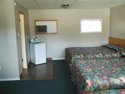 a hotel room with two beds and a small refrigerator at Ponderosa Motor Inn in Golden