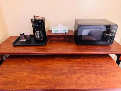 a microwave sitting on a wooden table next to cups at Island Travel Inn in Victoria