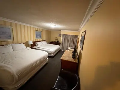a hotel room with two beds and a desk at Island Travel Inn in Victoria