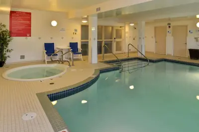 a swimming pool in a large room with a table and chairs at Holiday Inn Express Edmonton North by IHG in Edmonton