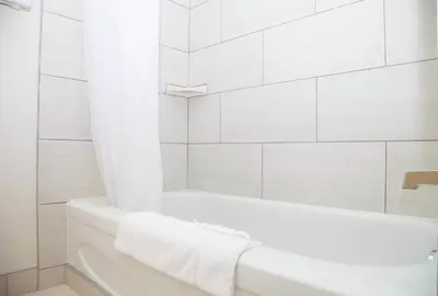 a white bathroom with a tub and a shower at Twin Pine Inn & Suites in Hinton