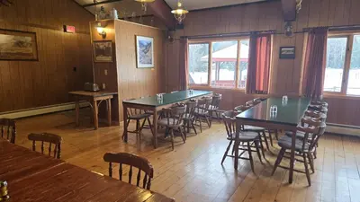 a dining room with tables and chairs and windows at Black Cat Guest Ranch in Brule Mines