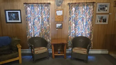 two chairs and a table in a room with curtains at Black Cat Guest Ranch in Brule Mines