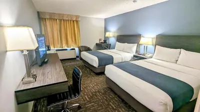 a hotel room with two beds and a desk at Crestwood Hotel in Hinton