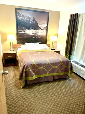 a hotel room with a bed and a painting on the wall at Super 8 by Wyndham Hinton-Free Breakfast,Wifi,Parking in Hinton