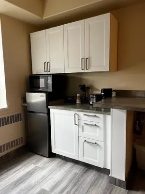 a kitchen with white cabinets and a black refrigerator at Athabasca Valley Inn & Suites in Hinton