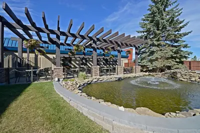 a pond in a yard with a wooden pergola at Best Western Wayside Inn in Wetaskiwin