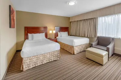 a hotel room with two beds and a chair at Days Inn by Wyndham Terrace in Terrace