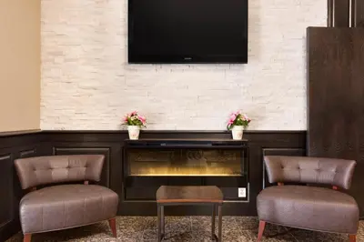 a fireplace with two chairs and a television on a wall at Days Inn by Wyndham Terrace in Terrace