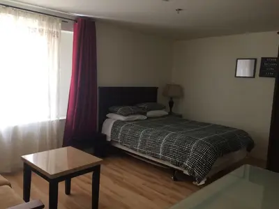 a bedroom with a bed and a table and a window at Black Rooster Guesthouse in Prince Rupert