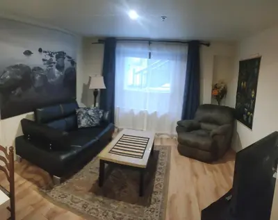 a living room with a couch and a chair and a table at Black Rooster Guesthouse in Prince Rupert