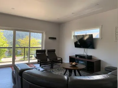 a living room with a couch and a flat screen tv at Black Rooster Guesthouse in Prince Rupert