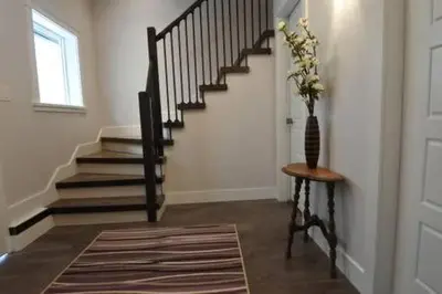 a hallway with a staircase with a vase of flowers at Black Rooster Guesthouse in Prince Rupert