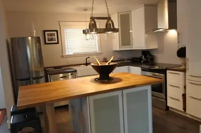 a kitchen with a wooden island with a bowl on it at Black Rooster Guesthouse in Prince Rupert