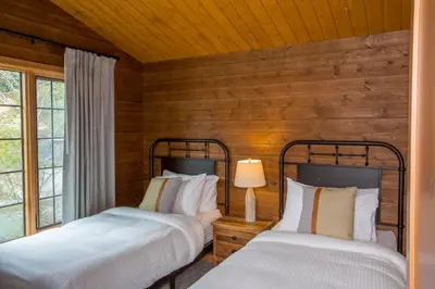 two beds in a room with wooden walls at Bear Hill Lodge in Jasper