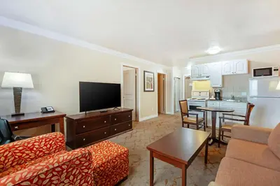 a living room with a couch and a tv and a kitchen at Best Western PLUS Mirage Hotel and Resort in High Level