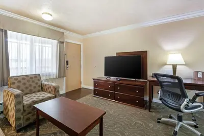 a living room with a television and a desk and chair at Best Western PLUS Mirage Hotel and Resort in High Level