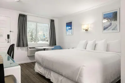 a white bedroom with a large bed and a window at SureStay Hotel by Best Western Rossland Red Mountain in Rossland