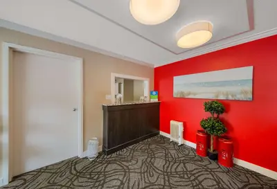 a room with a red wall with a vanity and a mirror at SureStay Hotel by Best Western Rossland Red Mountain in Rossland