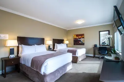 a hotel room with two beds and a desk at Regent Hotel Revelstoke in Revelstoke
