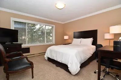 a bedroom with a bed and a desk and a window at Regent Hotel Revelstoke in Revelstoke