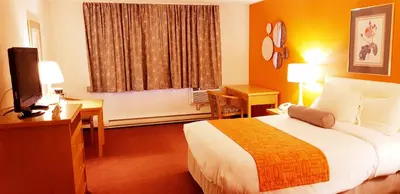 a hotel room with a bed and a desk and a television at Howard Johnson by Wyndham Fort St. John in Fort Saint John