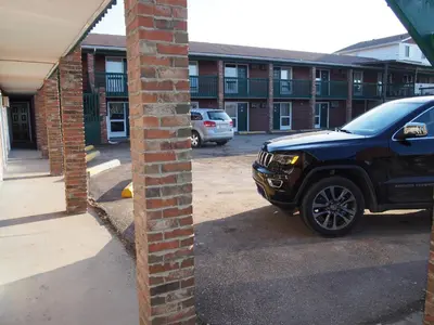 a car parked in a parking lot next to a brick building at Airways Motel in Cold Lake