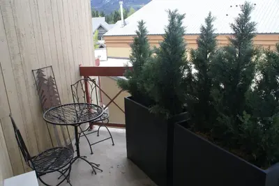 a patio with two potted trees and a table and chairs at Whistler Superior Properties in Whistler