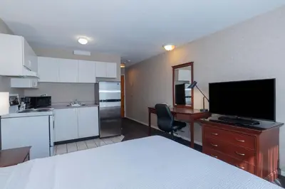 a room with a kitchen with a bed and a television at Sandman Hotel Penticton in Penticton