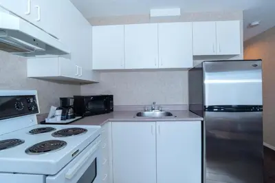 a kitchen with white cabinets and a stainless steel refrigerator at Sandman Hotel Penticton in Penticton