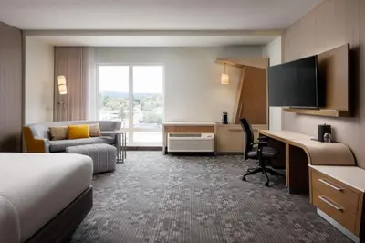 a hotel room with a bed and a desk with a computer at Courtyard by Marriott Prince George in Prince George
