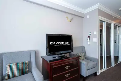 a living room with a tv and two chairs at Sandman Hotel & Suites Prince George in Prince George