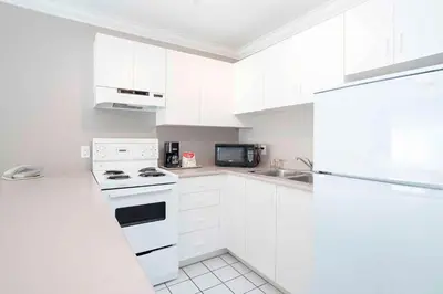 a white kitchen with a stove and a microwave at Sandman Hotel & Suites Prince George in Prince George