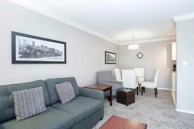 a living room with a couch and a dining room at Sandman Hotel & Suites Prince George in Prince George