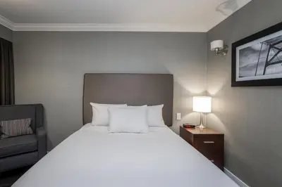 a bedroom with a large white bed and a chair at Sandman Hotel Revelstoke in Revelstoke